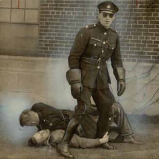 Held Down on the ground, a striker struggles with a policeman as another officer stands guard