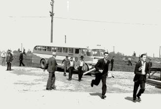 Men Replacing the strikers dash in a hurry from their bus in an effort to get aboard the Noronic while police stand guard to keep their opponents away(...)