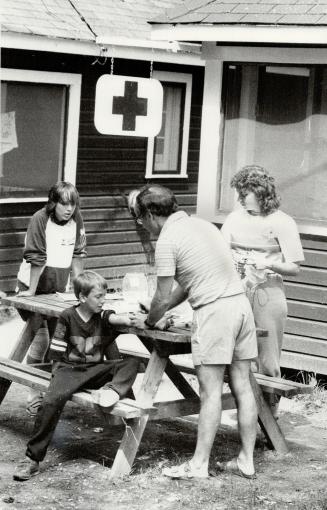 Medical attention: Dr. Don Norris administers treatment to hemophillac Geoff Hershkiwitz, 8, outside the camp hospital, aided by camp nurse Sharon Shultz