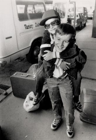 Off to summer camp, John Leclair, 9, gets piggy-back ride from brother Michael, 12, today after they arrive in Toronto from Sudbury en route to Camp Trillium in Picton