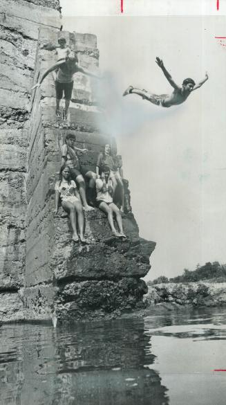 Flying from the heat, three boys dive together from the 25-foot-high Erindale Dam for a cooling dip in the feet of water in the Credit River below. To(...)