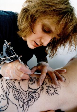 Human detail: Left, tattoo artist Bill Baker, shown working on a black outline, says the tattooist acts as draftsman for his client's dream world or beliefs