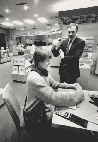 Under the gun: Petra Chevrier, 28, seated, finishes off the very last tax return at The Atrium on Bay postal station, as station superintendent Gerald Legere waits patiently