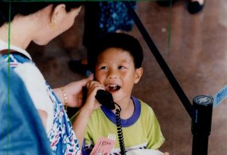 A boy named Jinqyan, 7, talks to relative in China during United Communications' celebrations of its second anniversary in the long-distance market. A(...)