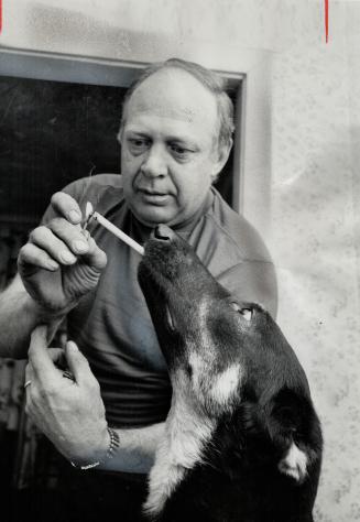 Pooch takes a puff .. then 'Drops Dead'. Athena, the smoking dog, takes a puff from a cigarette lit by her owner Peter Nicholson. Next step in the act(...)