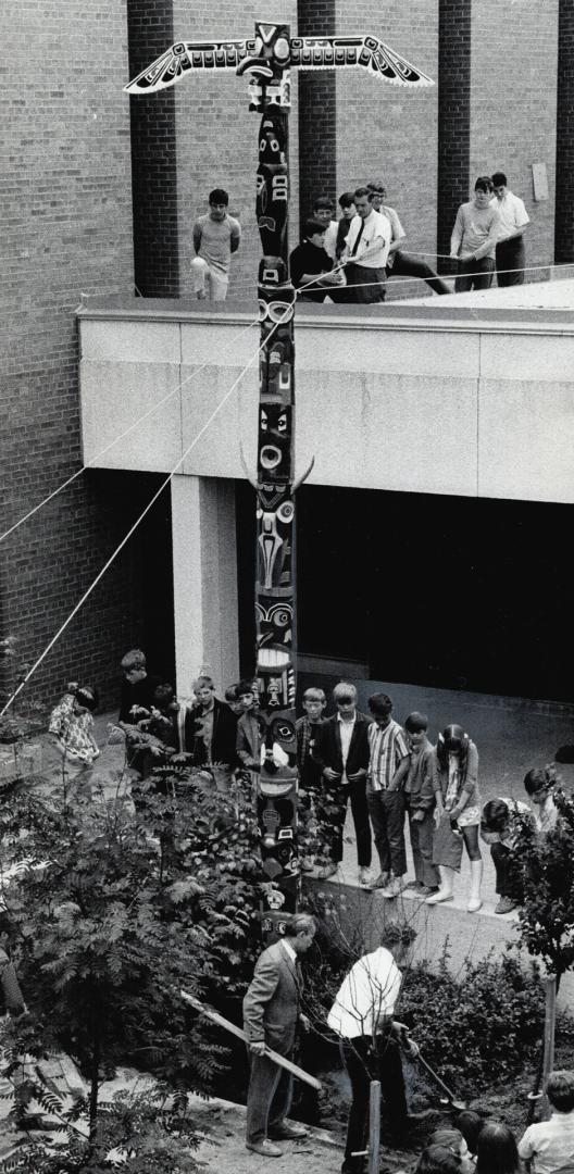 A Totem rises in metro, As students and staff of Woodbine Junior High School look on, 4 1/2 months of work are capped off as this totem pole, carved by pupils, is erected at school