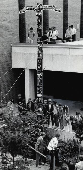 A Totem rises in metro, As students and staff of Woodbine Junior High School look on, 4 1/2 months of work are capped off as this totem pole, carved by pupils, is erected at school