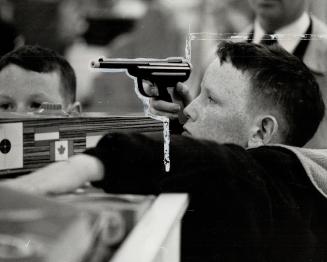 A young visitor to a Toronto department store takes aim with a toy pistol