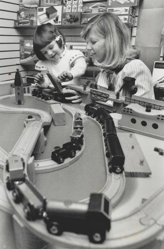 On track: Mastermind Educational store owner Barb Zoltok and Clair Grinstead, 2 1/2, work the crane on a wooden Brio train set, one of this year's popular Christmas choices