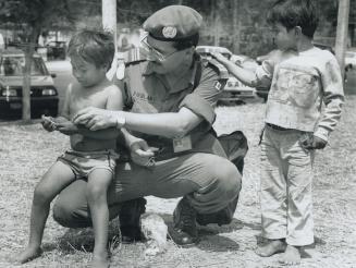 Making friends: Major Alex Fieglar shares candles with children in El Salvador during a Canadian peace-keeping mission