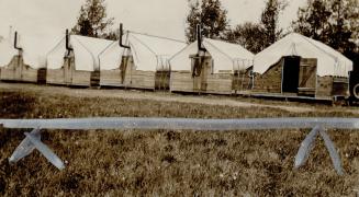 Forerunners of Highway camps, This board-walled tent camp is typical of those which probably will be built along the northern Ontario route of the tra(...)