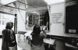 License in danger: Employee Roman Kolee serves fries to a customer from a truck owned by Chris Blue, parked outside the Westin Harbour Castle Hotel