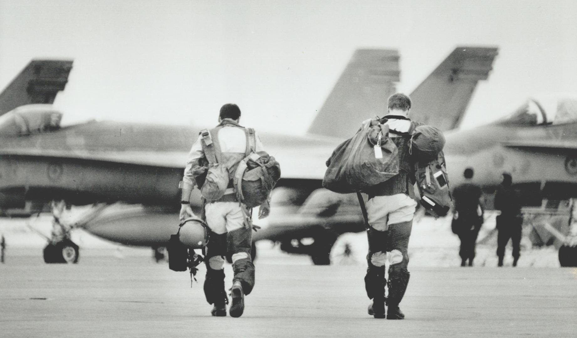 Ready for battle, Two Canadian pilots, loaded with gear, head to their CF-18s at Canada Dry 2 near Qatar