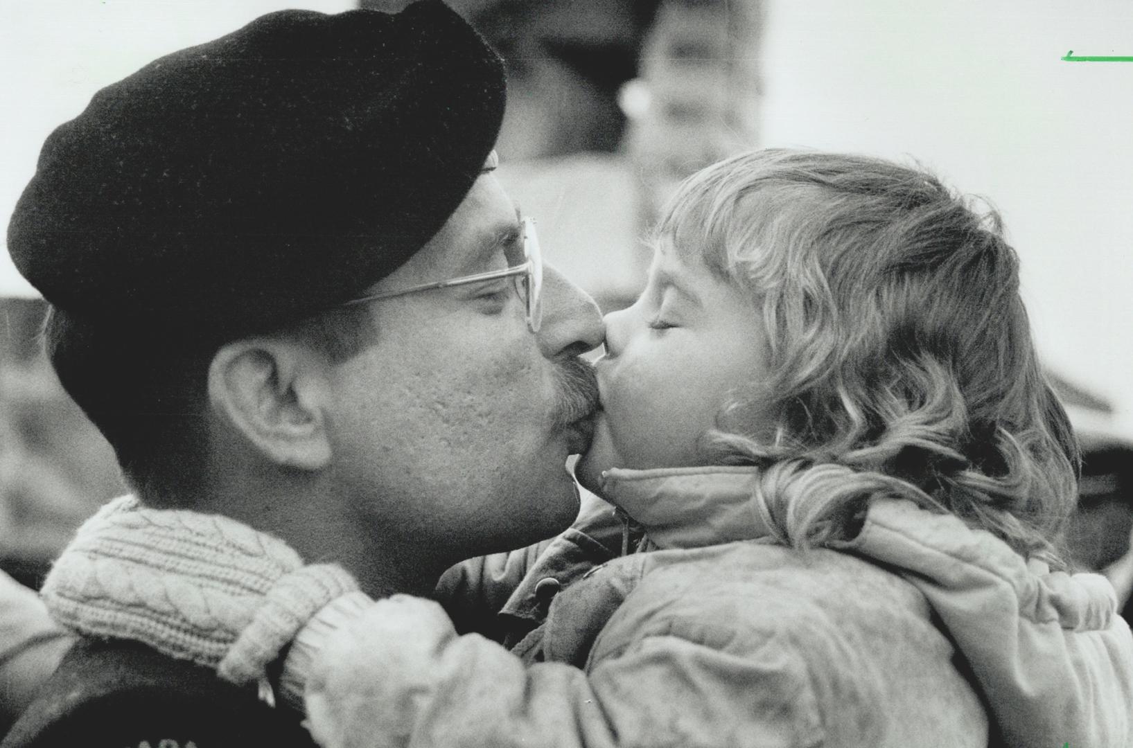 Dads Ahoy: A little lad, above left, scans the horizon for his father while a young girl, right, bestows a welcoming kiss on hers