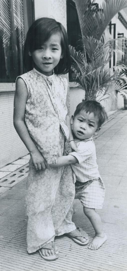 Taking care of younger brother in front of their parents store