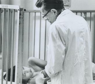 Dr Alex Halbert gives a comforting pat to an orphan he is checking over