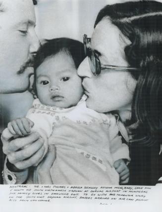 A war orphan from Cambodia, Suvann Ratha, 5 months old, gets welcoming kisses in Montreal last night from her new parents, Thomas and Adela Beasley of(...)