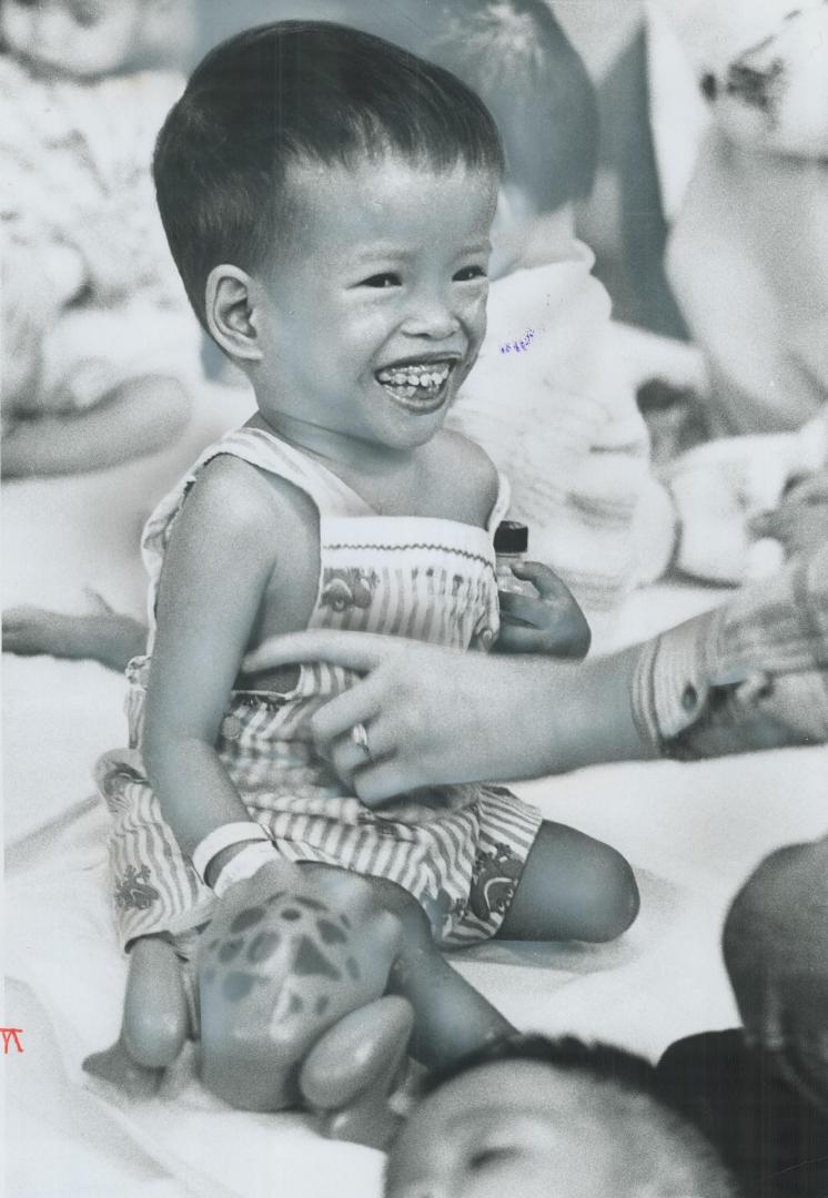 Safe in Canada, 3-year-old Marth Nguyen Thi Phuong Mai, smiles broadly as he's tickled under his arm by a government worker at the Surrey Place Centre(...)
