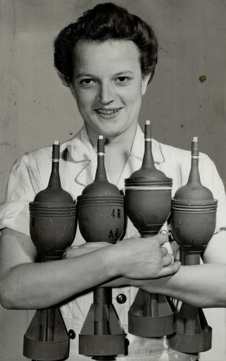 Miniature bombs held by Miss Vivian Baker at Piat, projectiles similar to those used by Canada's new V