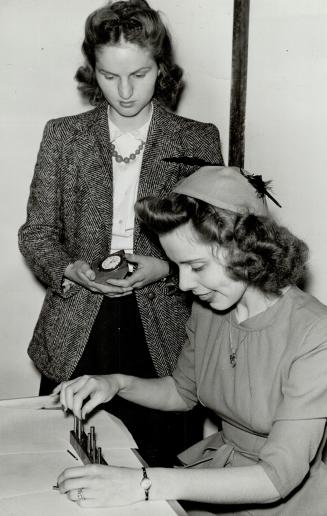 Here Dorothy Norwood holds the stop watch on Miss Secor in one of the tests designed to speed up selection of suitable workers