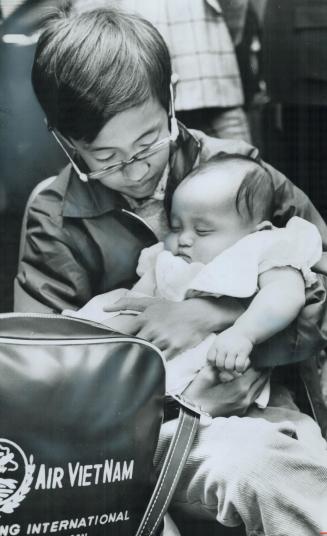 Cradling baby sister in his arms last night at Toronto International Airport is 9-year-old Thanh Ha Tu
