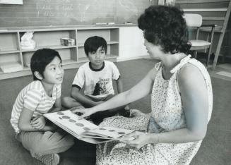 Viet Nam refugees Luu Huy Vien, left, and Luong Cam Xuong concentrate on teacher Janet Hoosen's English lessons