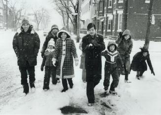 Duong Canh than and his family sample the aftermath of a Canadian snow storm outside their home