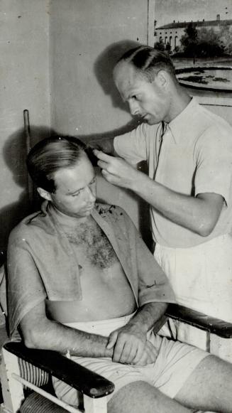 A German internee cuts the hair of a fellow prisoner in the camp barber shop