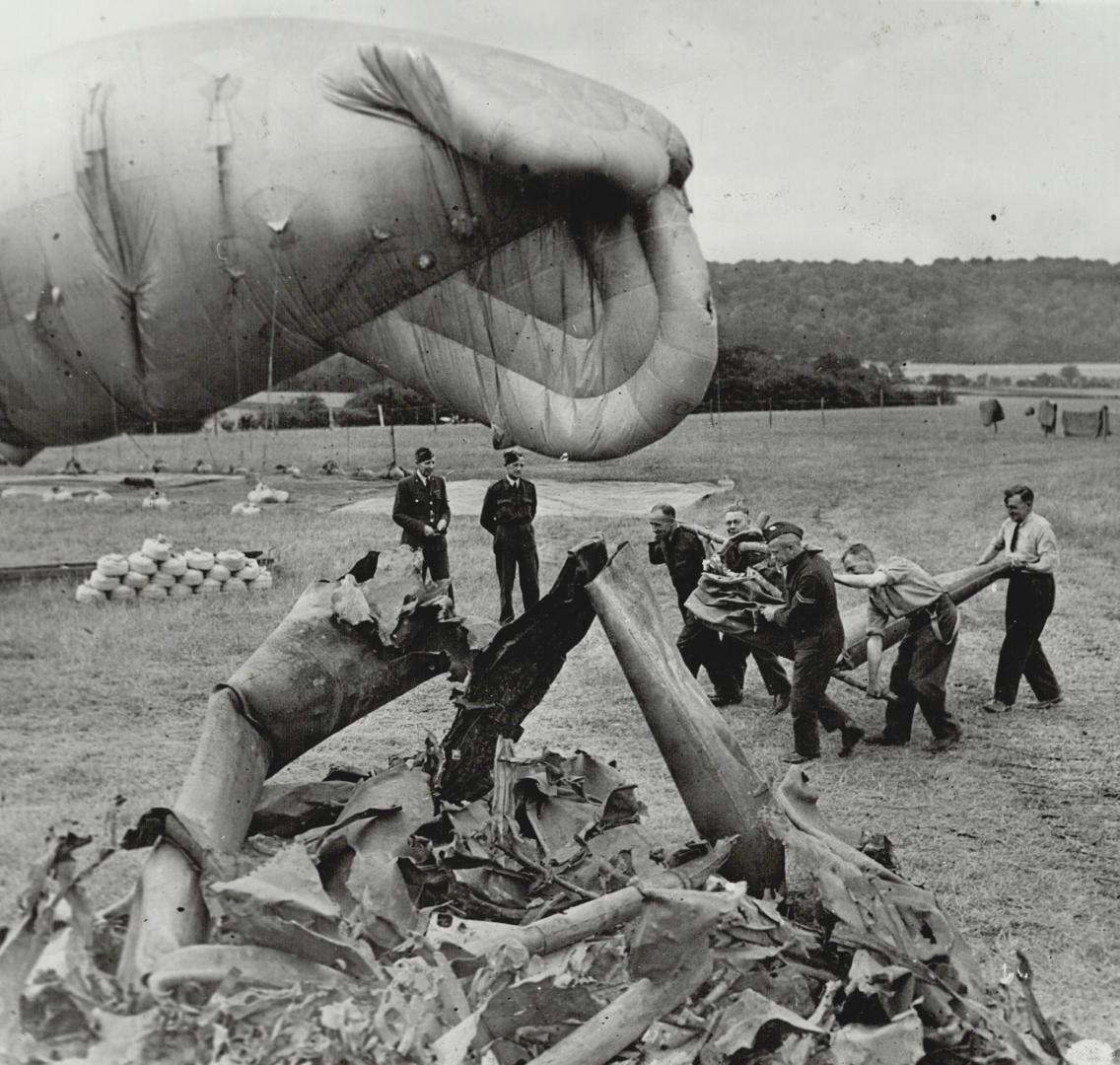 R.a.f. Men work together to pile parts of many flying bombs brought down by large balloon defences