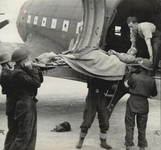 Near the front, a wounded Briton is taken from an ambulance and placed in a plane for transport to Britain
