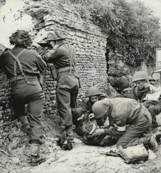 Ignoring the Danger of flying bullets, a Canadian padre works quickly and efficiently with Army Medical Corps men in evacuating wounded from a front l(...)