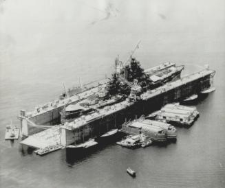 Battleship Mississippi restes in a huge floating drydock for repairs in the Philippines after and attack by a Kamikaze plane. By pumping out 700,000 g(...)