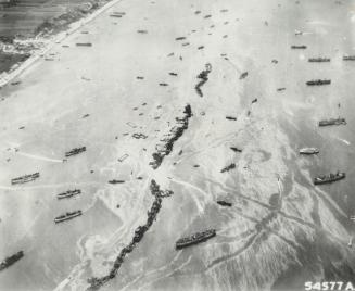 Lying in line off a Normandy beach in this air view are 13 Liberty ships scuttled to form the breakwater of a prefabricated harbor built in England for the invasion