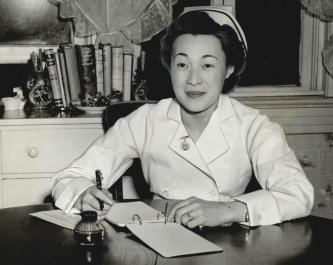 Woman in medical uniform writing on table 