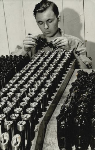 A young worker in a Canadian factory puts the finishing touches to a batch of grenades