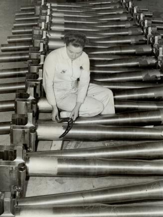Down in Quebec women are playing a big role in a gun plant and here Isobel MacKenzie inspects six-pounder gun parts
