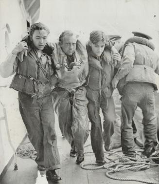 while a rescued prisoner is shown ABOVE BEING aided along deck