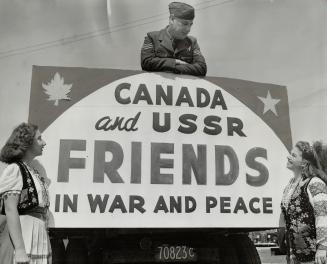 Friends all are Sergt. Ted Wall, perched above that sigh of Canadian-U.S.S.R. friendship, and the two Russian-born girls. Catherine Spack and Lina Ewa(...)