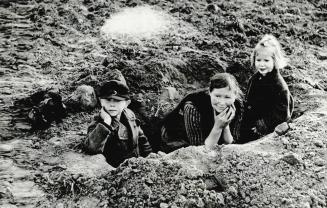 Airborne troops are landing all around this German woman and her children who have taken refuge in a fox hole on the Rhine's east bank
