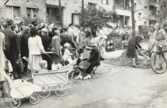Lining up in Berlin, men, women and children wait before a potato pile in a street to receive their rations of potatoes