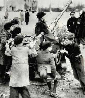 Soldiering the name of this group of German children shown with an old ann-aircraft gun located inner the centre of Berlin. Guns like this are scattered throughout the capital [Incomplete]