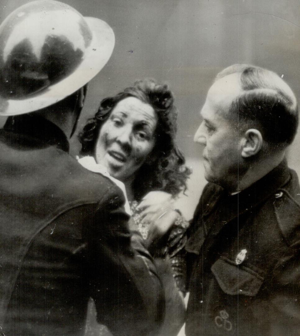 Her agonized Face showing the extent of her wounds, a woman robomb victim in England is aided by defence workers