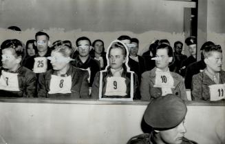 Women War Criminals on trial with other Nazis at Lueneberg, Germany, sit in the prisoners dock, wearing identification numbers, and listen to the proc(...)