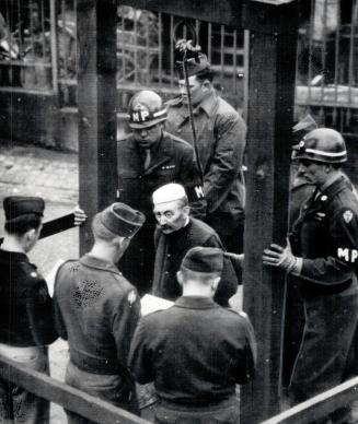 Hood and noose is placed over the head of a German civilian on the gallows at Bruchsal prison, Germay, for the murder of six American airmen shot down in 1944