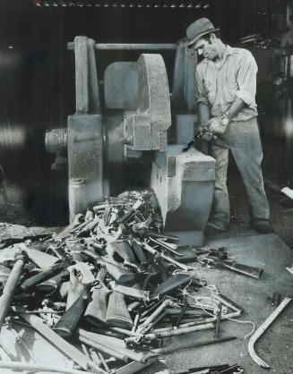 Dangerous haul: A small arsenal of handguns, rifles and shotguns seized by Metro police is destroyed in a metal crusher in this 1975 picture