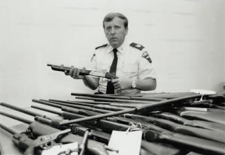 Formidable Firepower: Durham Region police Sergeant Archie Mackinnon shows a sawed-off shotgun and other weapons turned in during gun amnesty
