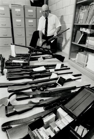 Seized Rifles: Deke McBrien of the Metro police firearm registration unit examines guns seized in a Scarborough raid last year, when police raised alarms over bank robbery rates