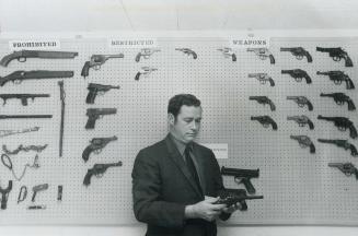 S/Sgt. Mat MacPherson of the Burlington police department examines the gun a man used to commit suicide, one of the more than 50 weapons in his collec(...)
