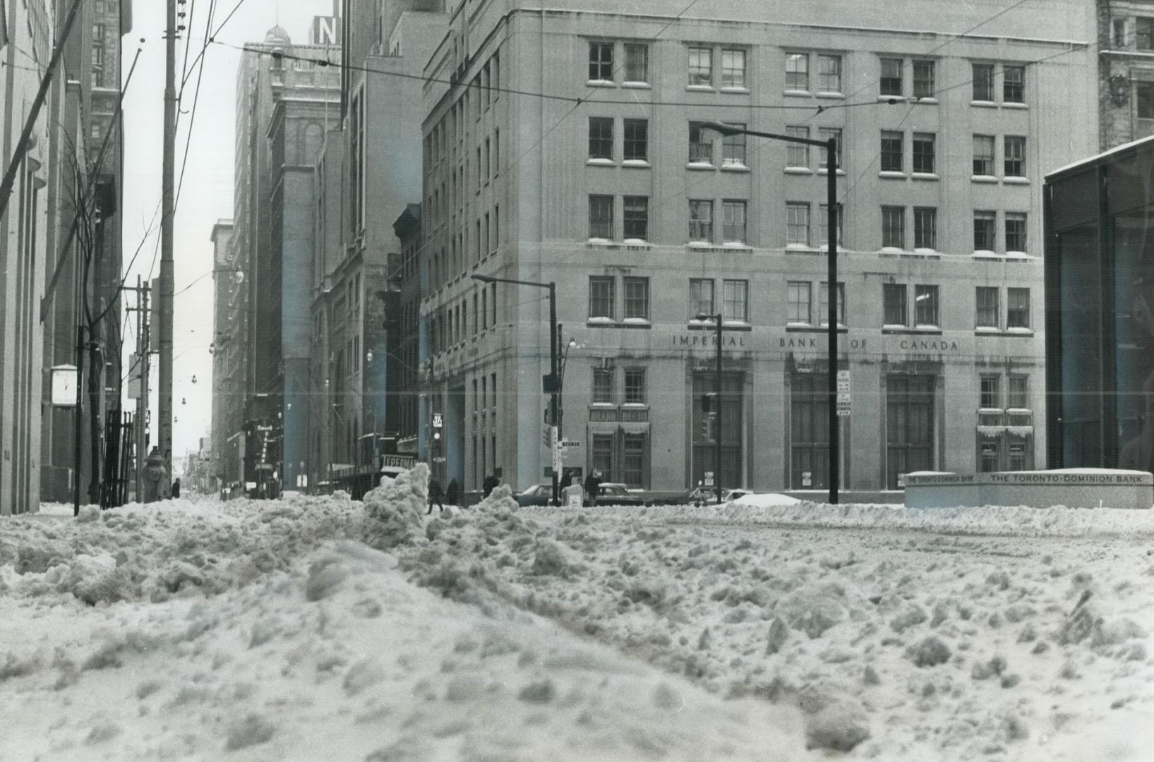 Strangled in winter's grip, Toronto downtown intersection of King and Bay stands empty except for gently falling snow yesterday while city snowplows f(...)
