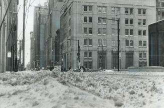 Strangled in winter's grip, Toronto downtown intersection of King and Bay stands empty except for gently falling snow yesterday while city snowplows f(...)